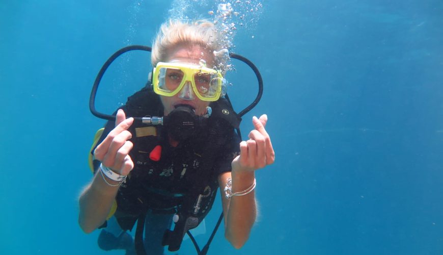 Snorkeller in a yellow mask swimming in clear blue water at Ras Mohammed in the Red Sea